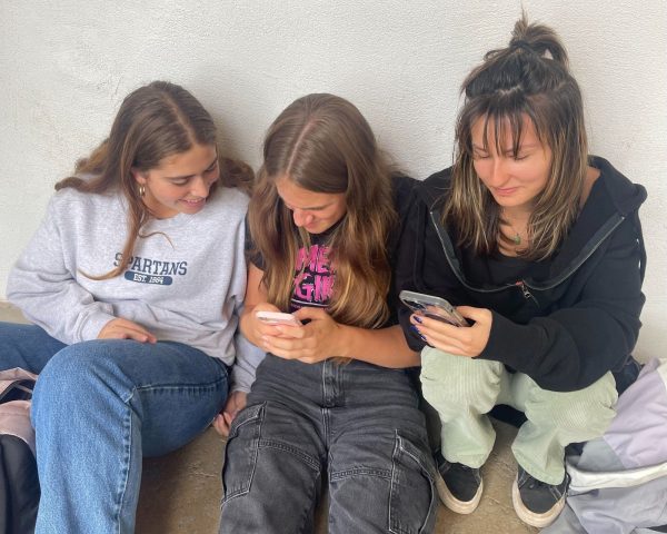 Three Seabury Hall juniors posing on their cell phones during lunch in the hallway on Friday
